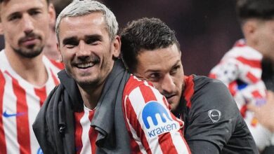 Two football players in red-and-white striped jerseys celebrate together, smiling after a match, with one wrapping an arm around the other’s shoulder in a joyful moment.