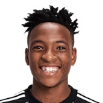 Portrait of a smiling man with short twisted hair against a white background, wearing a dark top.