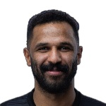 Close-up portrait of a man with dark hair and a short beard, smiling against a white background.