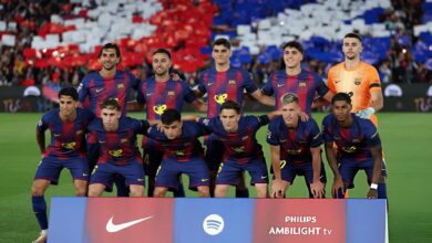 FC Barcelona players pose for a team photo on the field in blue-red kits, with a sponsor banner in front (Nike, Spotify, Philips Ambilight).